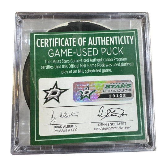A game-used hockey puck in a clear plastic protective case with a green and white Certificate of Authenticity insert. COA 