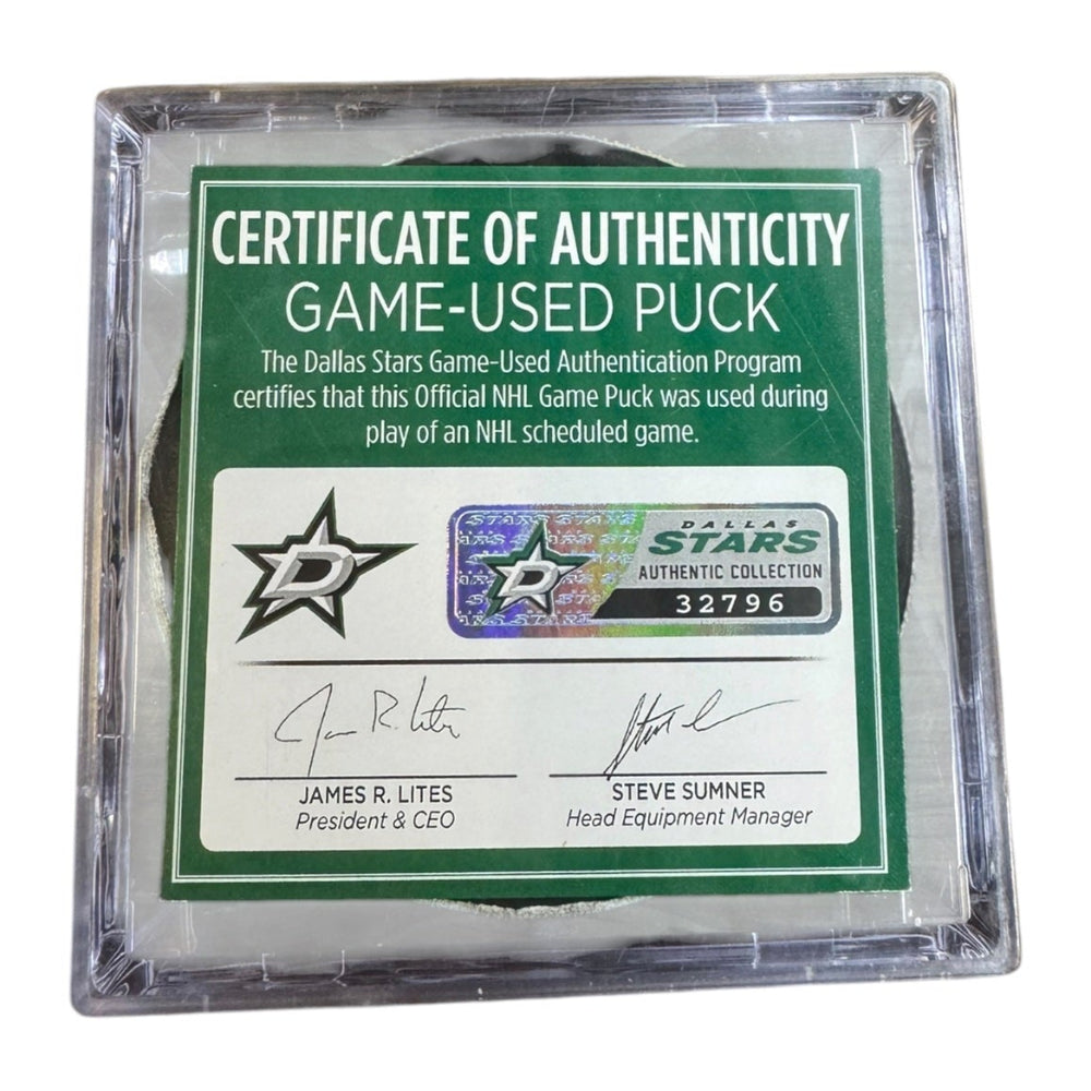A game-used hockey puck in a clear plastic protective case with a green and white Certificate of Authenticity insert. 
COA #32796