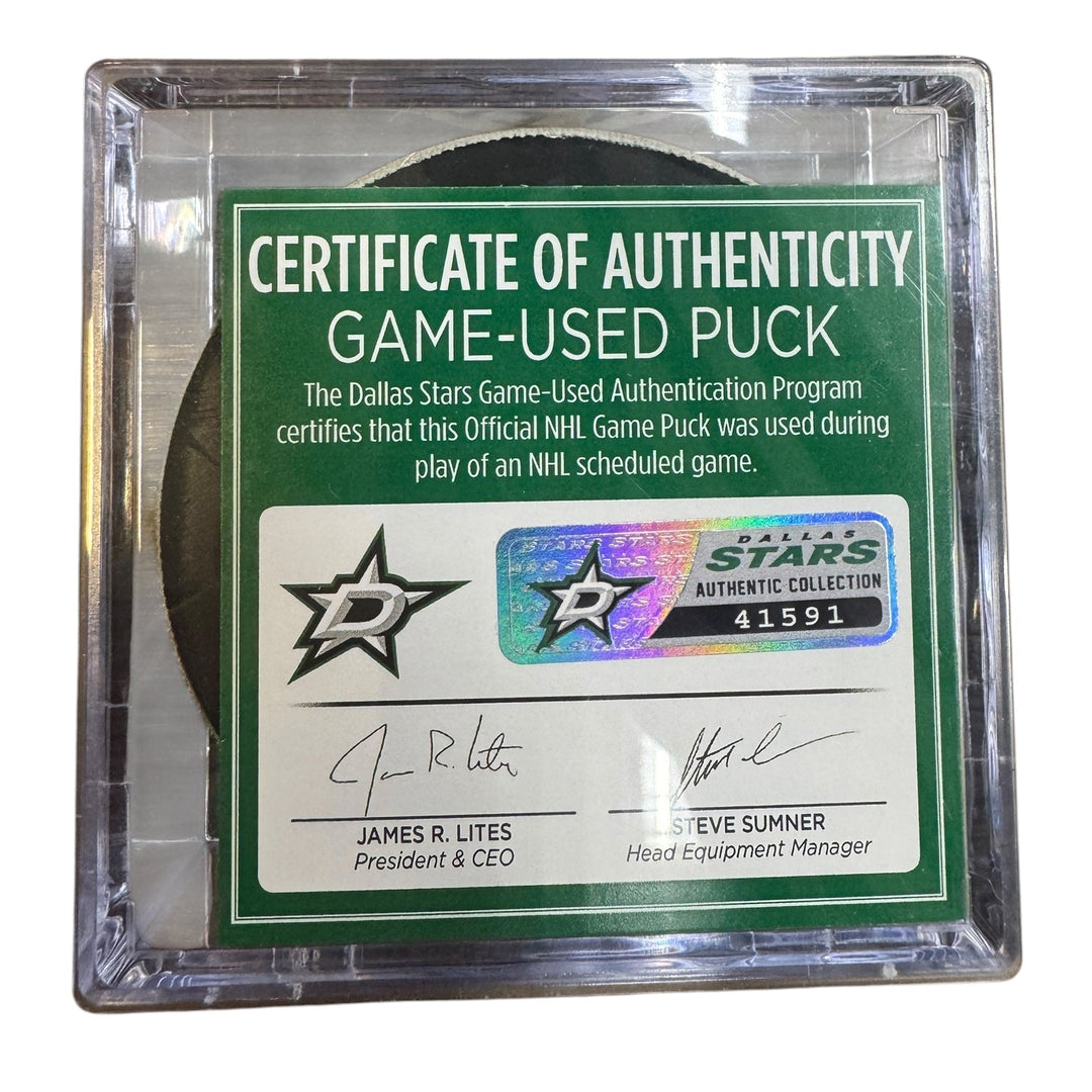 A game-used hockey puck in a clear plastic protective case with a green and white Certificate of Authenticity insert. 

COA 