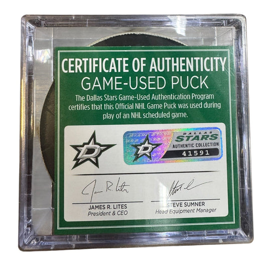 A game-used hockey puck in a clear plastic protective case with a green and white Certificate of Authenticity insert. 

COA 