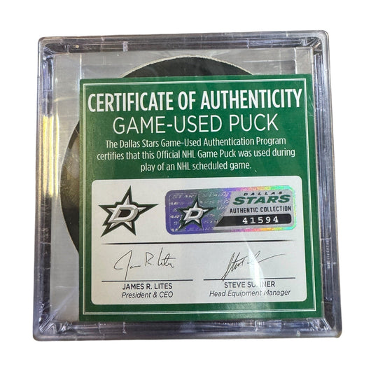 A game-used hockey puck in a clear plastic protective case with a green and white Certificate of Authenticity insert. 
COA 