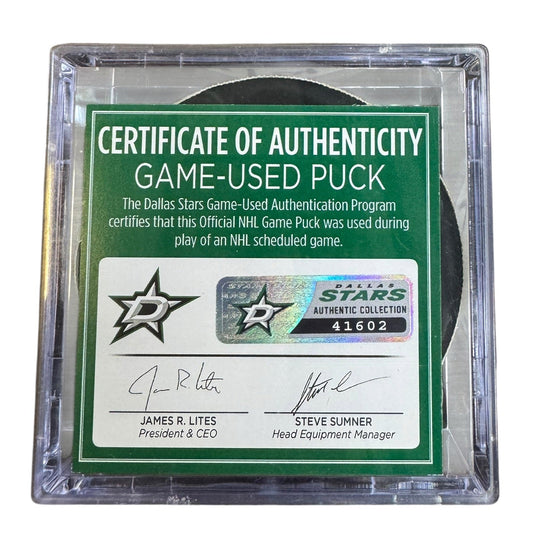 A game-used hockey puck in a clear plastic protective case with a green and white Certificate of Authenticity insert. 
COA 