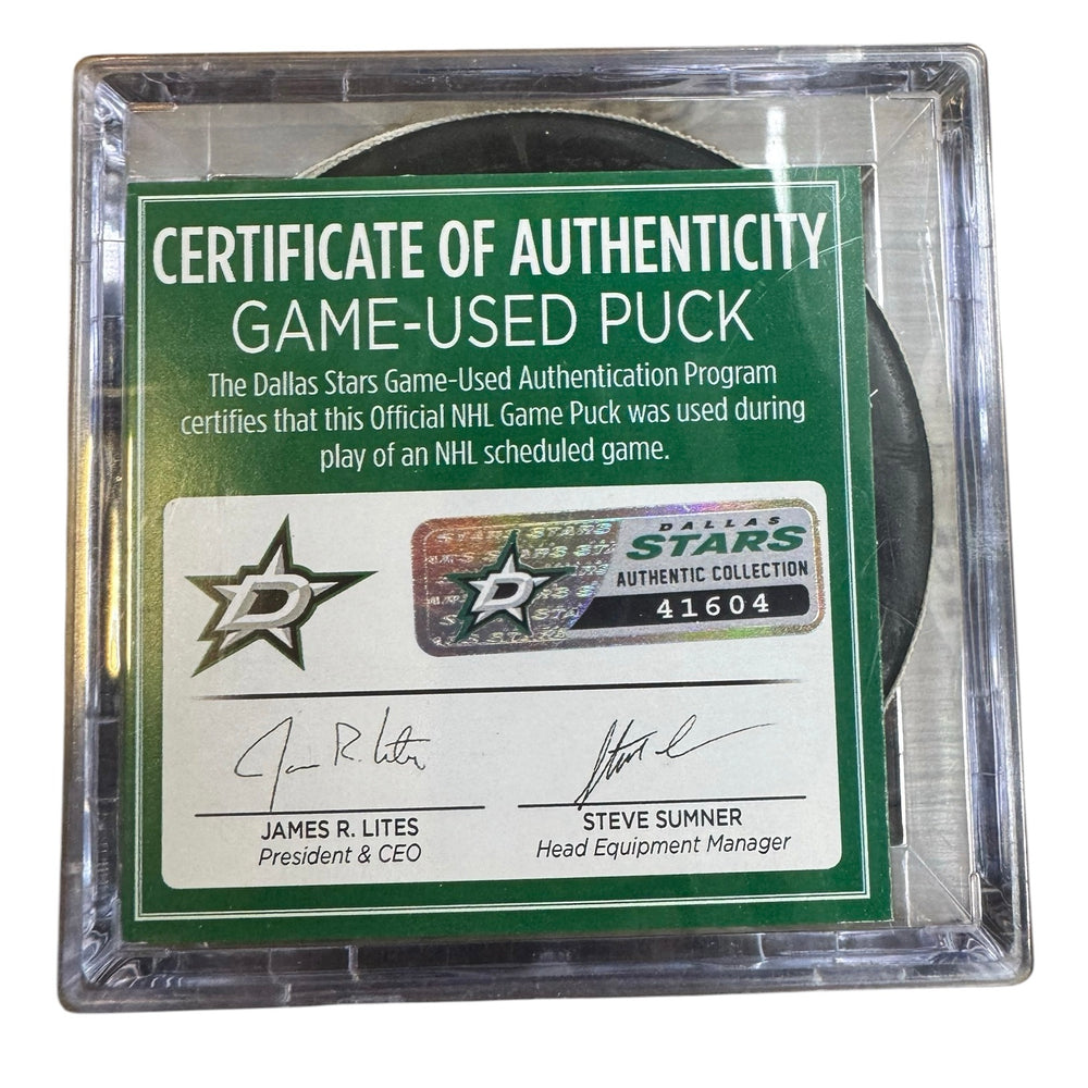A game-used hockey puck in a clear plastic protective case with a green and white Certificate of Authenticity insert. 
COA #41604