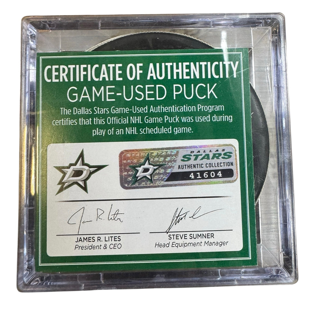 A game-used hockey puck in a clear plastic protective case with a green and white Certificate of Authenticity insert. 
COA 