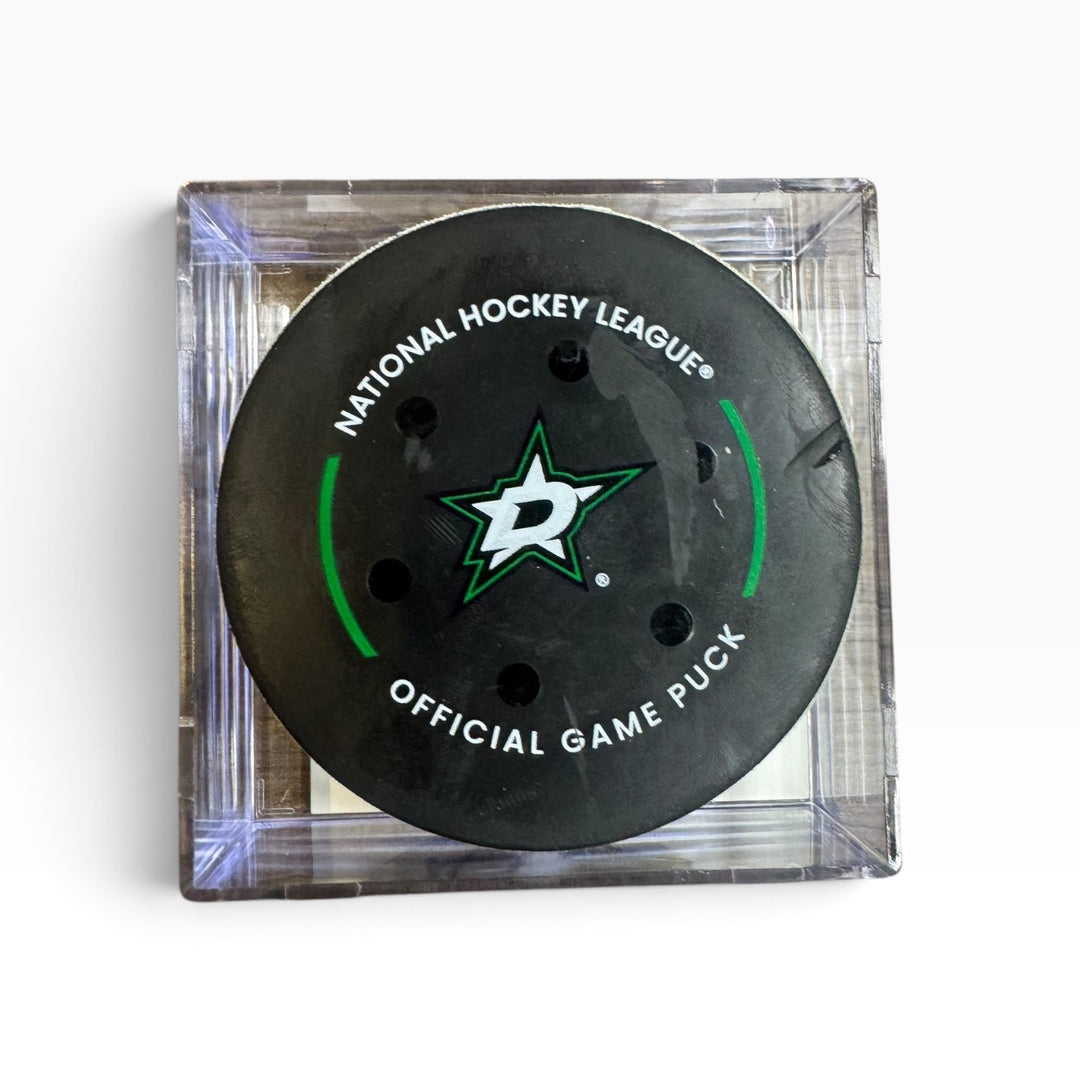 A Dallas Stars National Hockey League official game puck displayed inside a clear square plastic case on a white background.