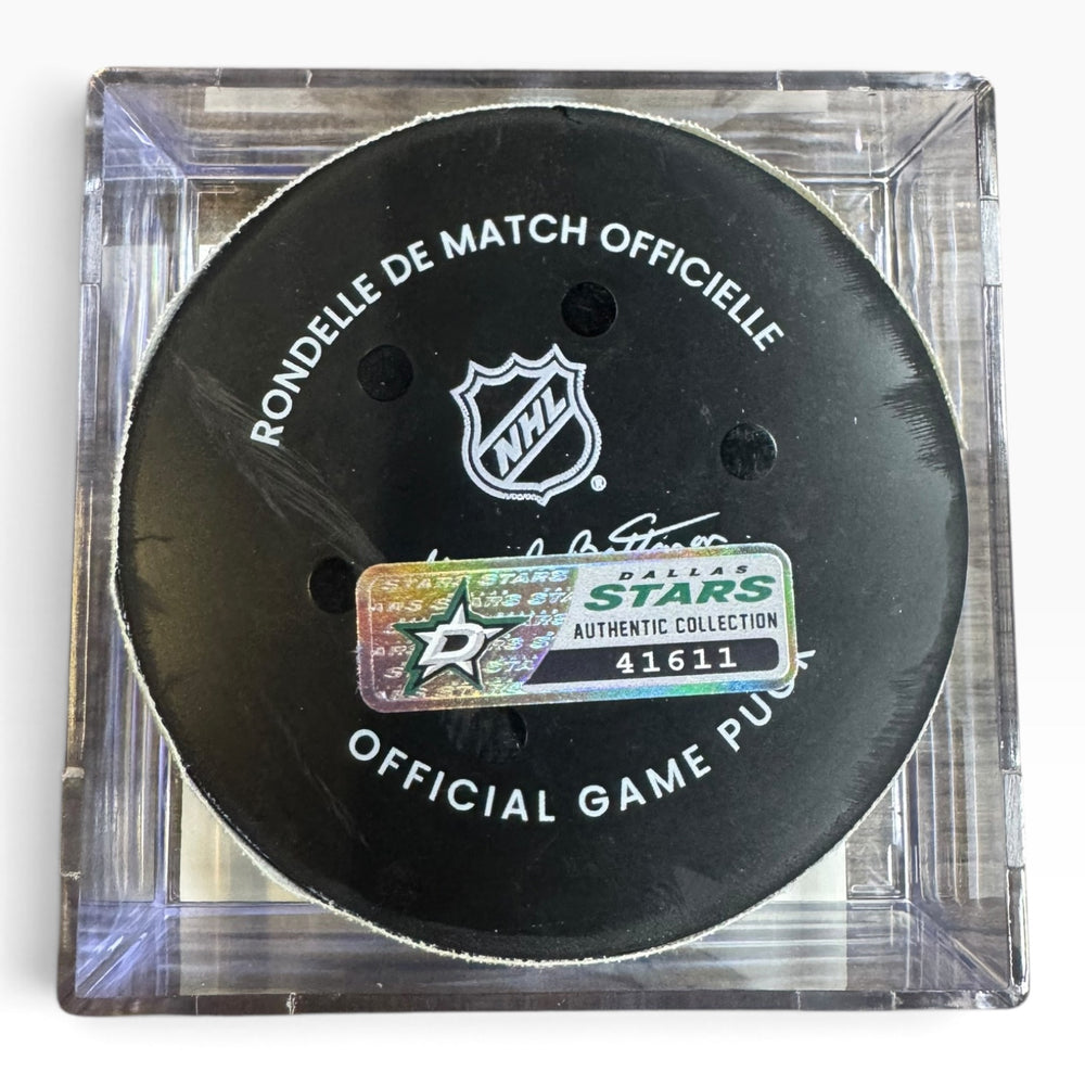 An official Dallas Stars hockey puck displayed inside a clear acrylic case. The black puck features white text reading 'RONDELL DE MATCH OFFICIELLE' and 'OFFICIAL GAME PUCK' along with the NHL shield logo and an authentic sticker.