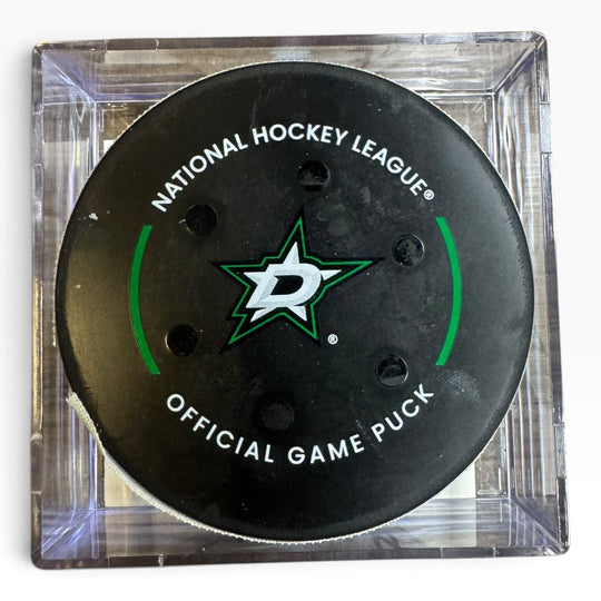 A Dallas Stars National Hockey League official game puck displayed inside a clear acrylic block, showing the black puck with its green and white logo.