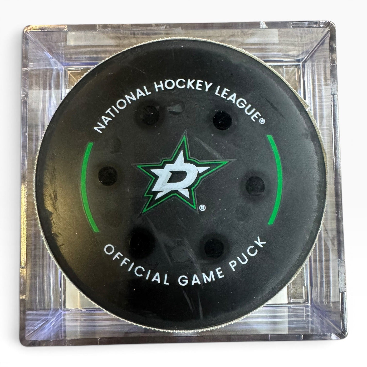 A Dallas Stars National Hockey League official game puck in a clear square display case, featuring the green and white team logo on a black puck.