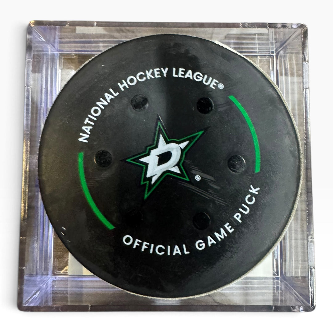 A Dallas Stars National Hockey League official game puck displayed inside a clear square acrylic case on a white background.