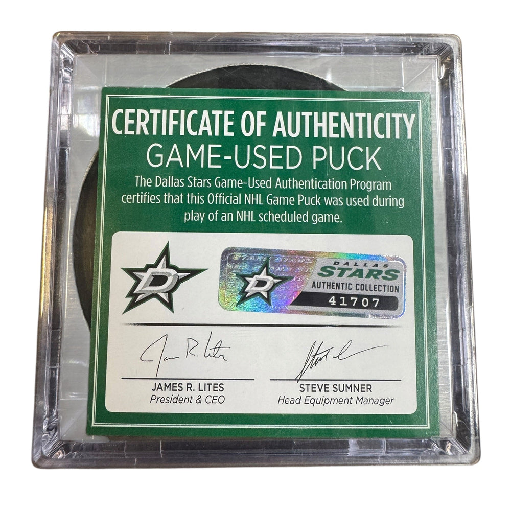 A game-used hockey puck in a clear plastic protective case with a green and white Certificate of Authenticity insert. 
COA #41707
