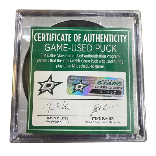 A game-used hockey puck in a clear plastic protective case with a green and white Certificate of Authenticity insert. 
COA 