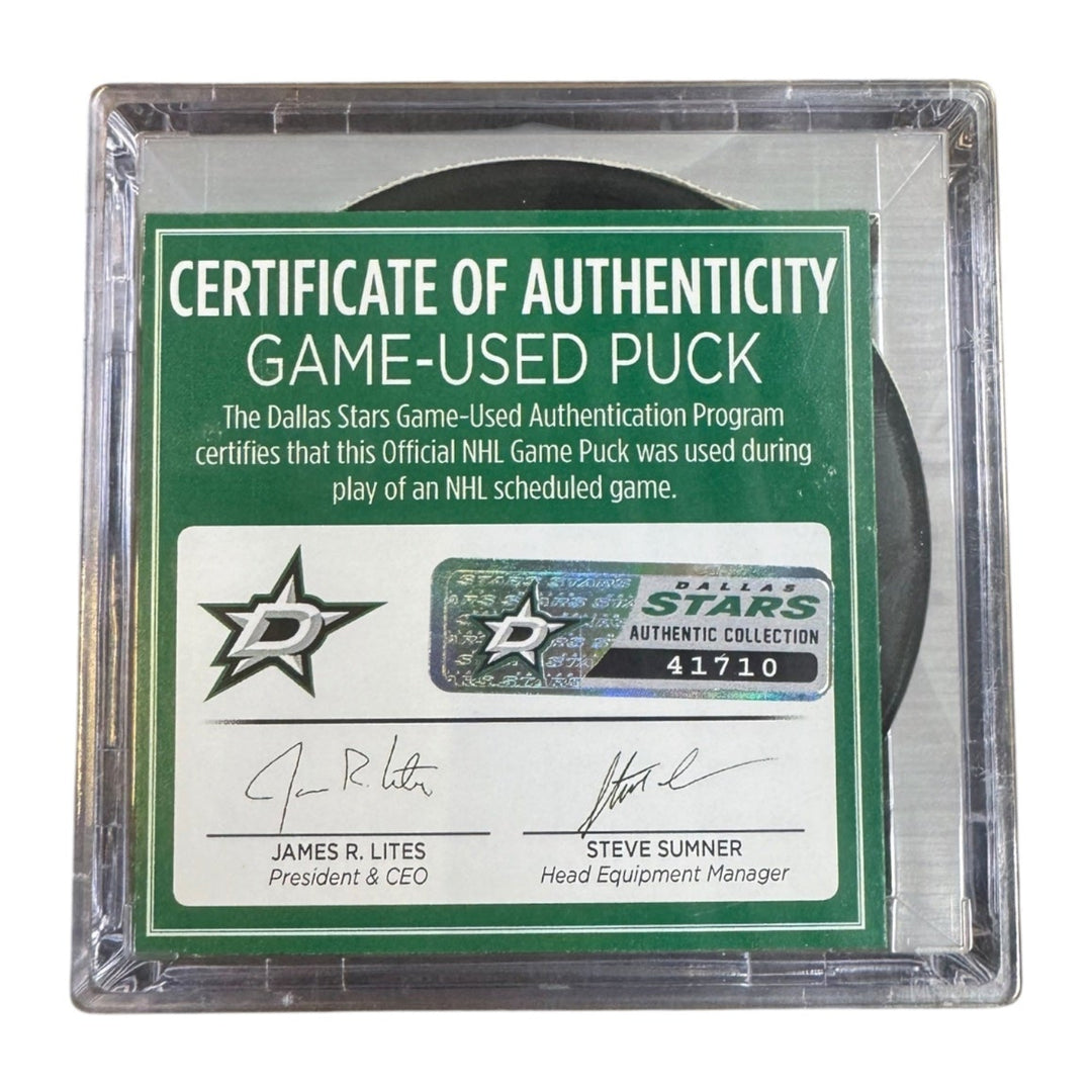 A game-used hockey puck in a clear plastic protective case with a green and white Certificate of Authenticity insert. 
COA 