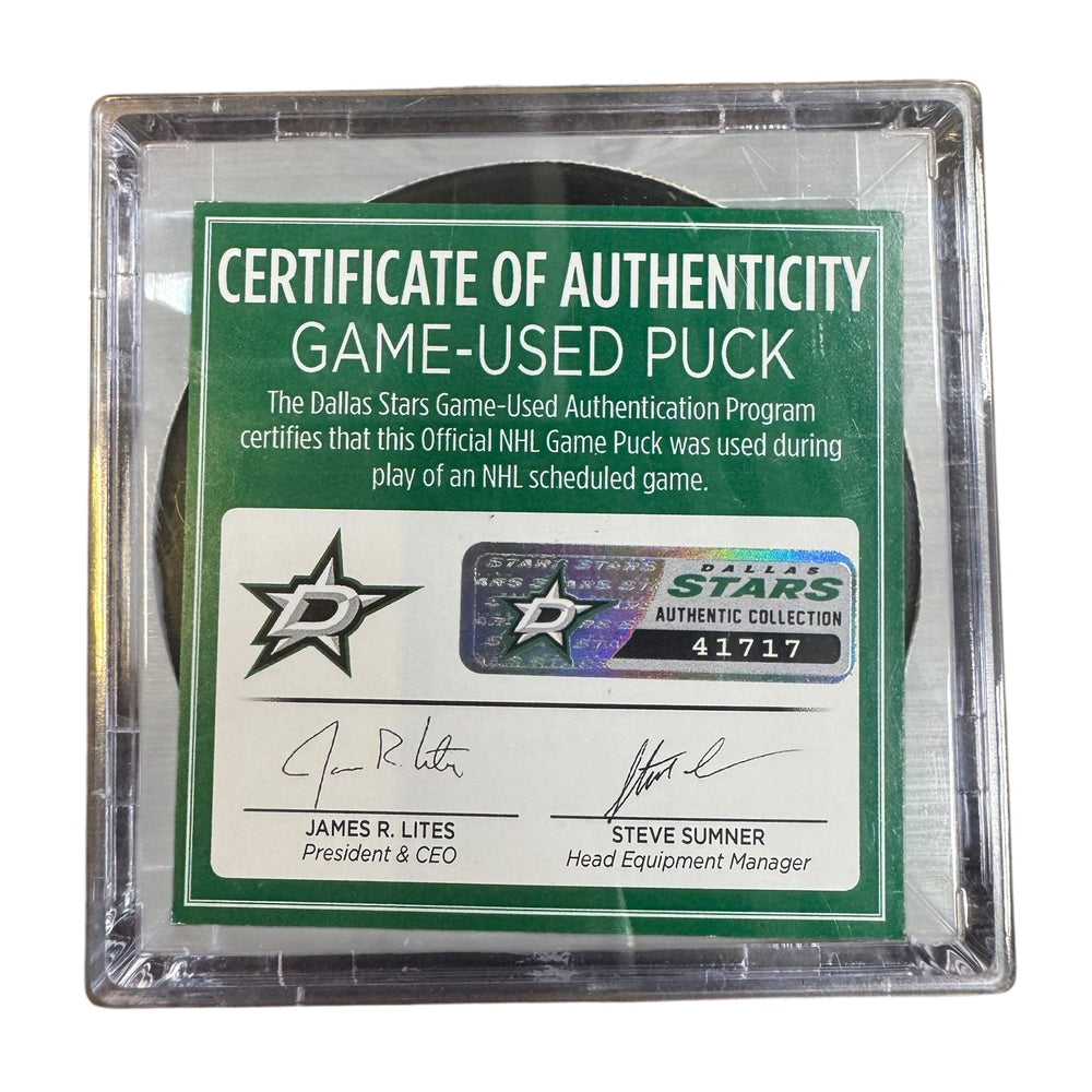 A game-used hockey puck in a clear plastic protective case with a green and white Certificate of Authenticity insert. 
COA #41717