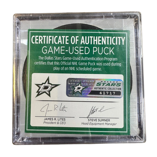 A game-used hockey puck in a clear plastic protective case with a green and white Certificate of Authenticity insert. 
COA 