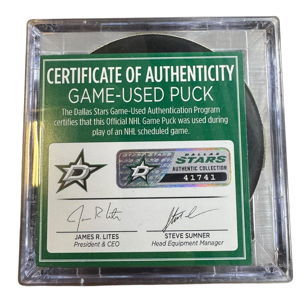 A game-used hockey puck in a clear plastic protective case with a green and white Certificate of Authenticity insert. 
COA #41741