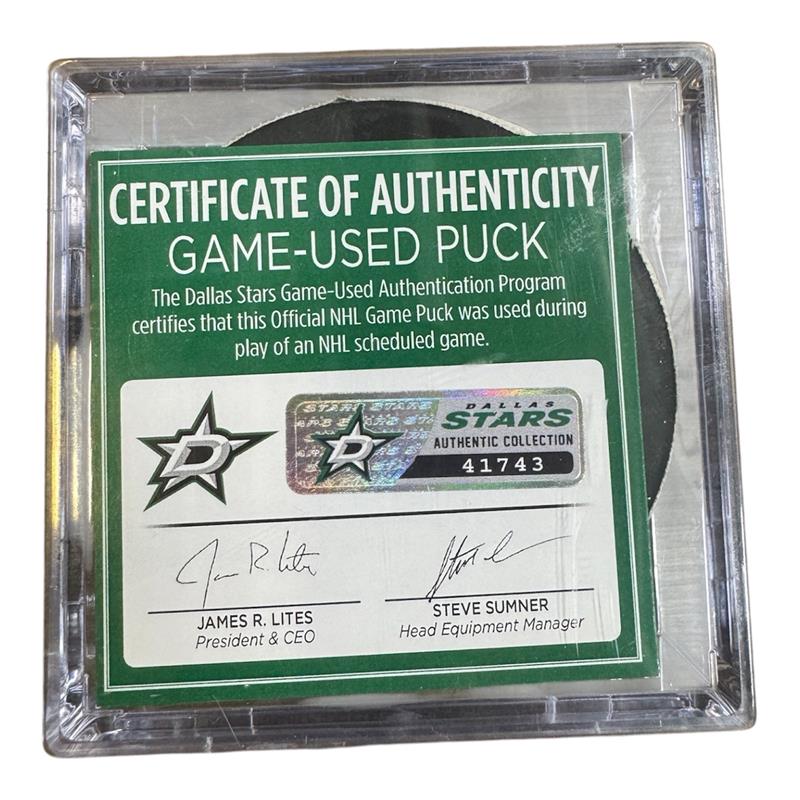 A game-used hockey puck in a clear plastic protective case with a green and white Certificate of Authenticity insert. 
COA 