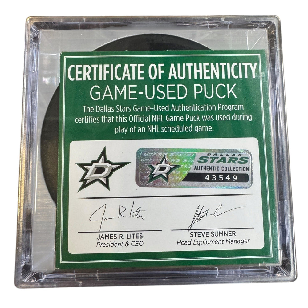 A game-used hockey puck in a clear plastic protective case with a green and white Certificate of Authenticity insert. 
COA #43549
