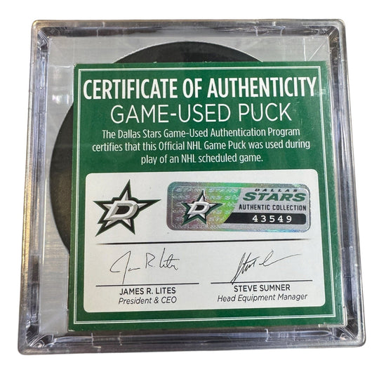 A game-used hockey puck in a clear plastic protective case with a green and white Certificate of Authenticity insert. 
COA 