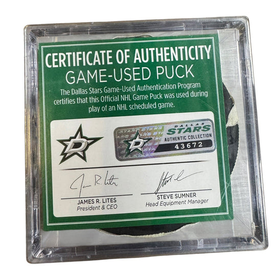 A game-used hockey puck in a clear plastic protective case with a green and white Certificate of Authenticity insert. 
COA 