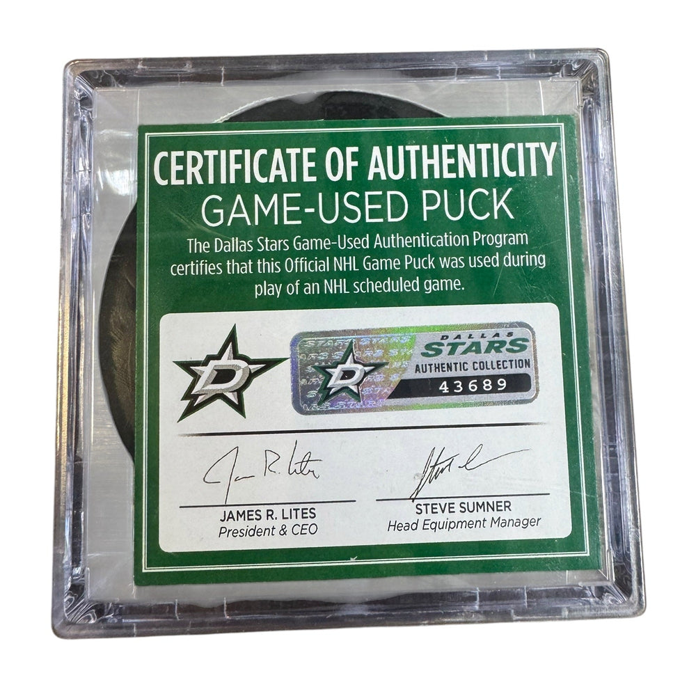 A game-used hockey puck in a clear plastic protective case with a green and white Certificate of Authenticity insert. 
COA #43689