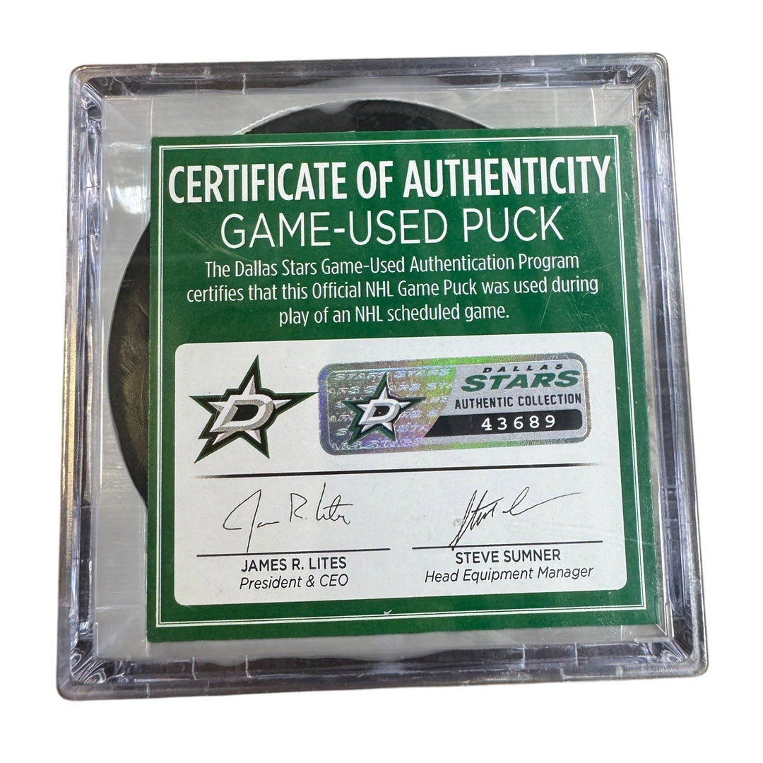 A game-used hockey puck in a clear plastic protective case with a green and white Certificate of Authenticity insert. 
COA 