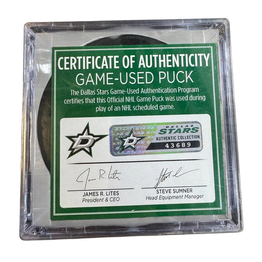 A game-used hockey puck in a clear plastic protective case with a green and white Certificate of Authenticity insert. 
COA 
