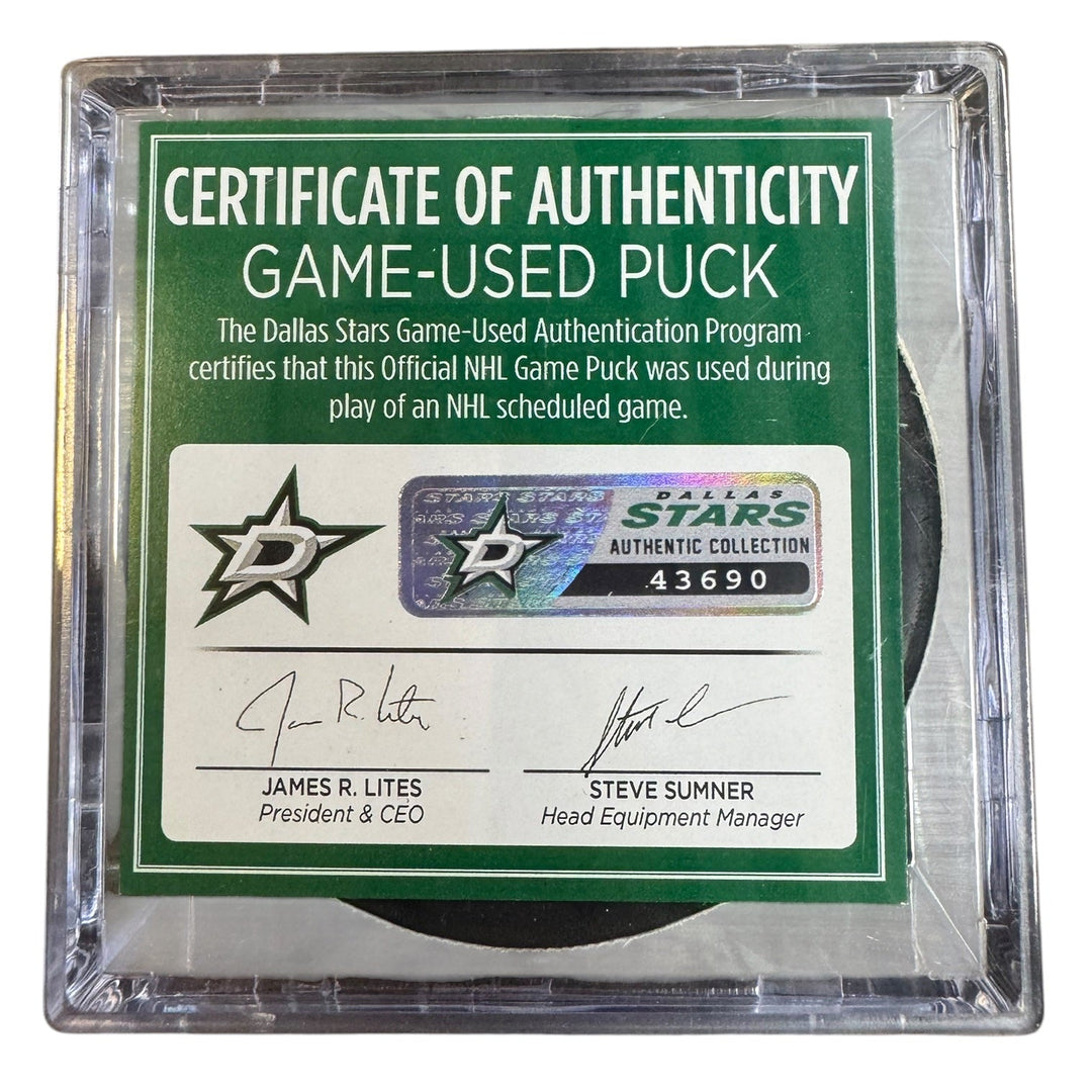 A game-used hockey puck in a clear plastic protective case with a green and white Certificate of Authenticity insert. 
COA 