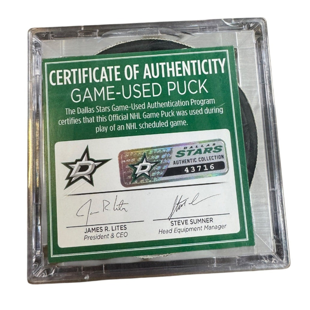 A game-used hockey puck in a clear plastic protective case with a green and white Certificate of Authenticity insert. 
COA 