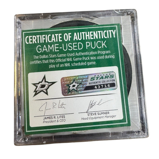 A game-used hockey puck in a clear plastic protective case with a green and white Certificate of Authenticity insert. 
COA 
