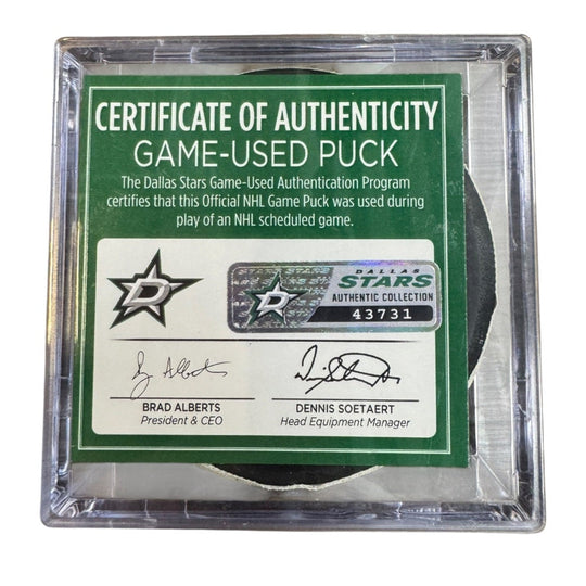 A game-used hockey puck in a clear plastic protective case with a green and white Certificate of Authenticity insert. 
COA 