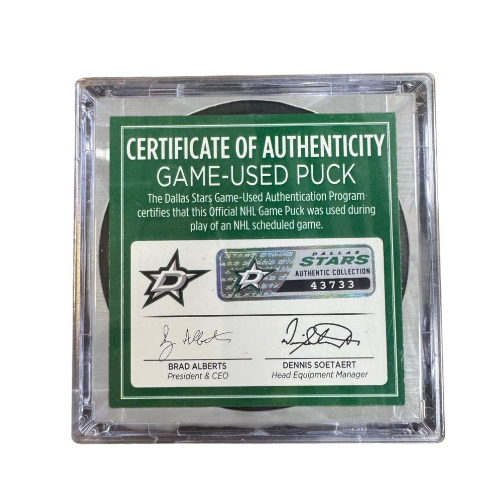 A game-used hockey puck in a clear plastic protective case with a green and white Certificate of Authenticity insert. 
COA #43733