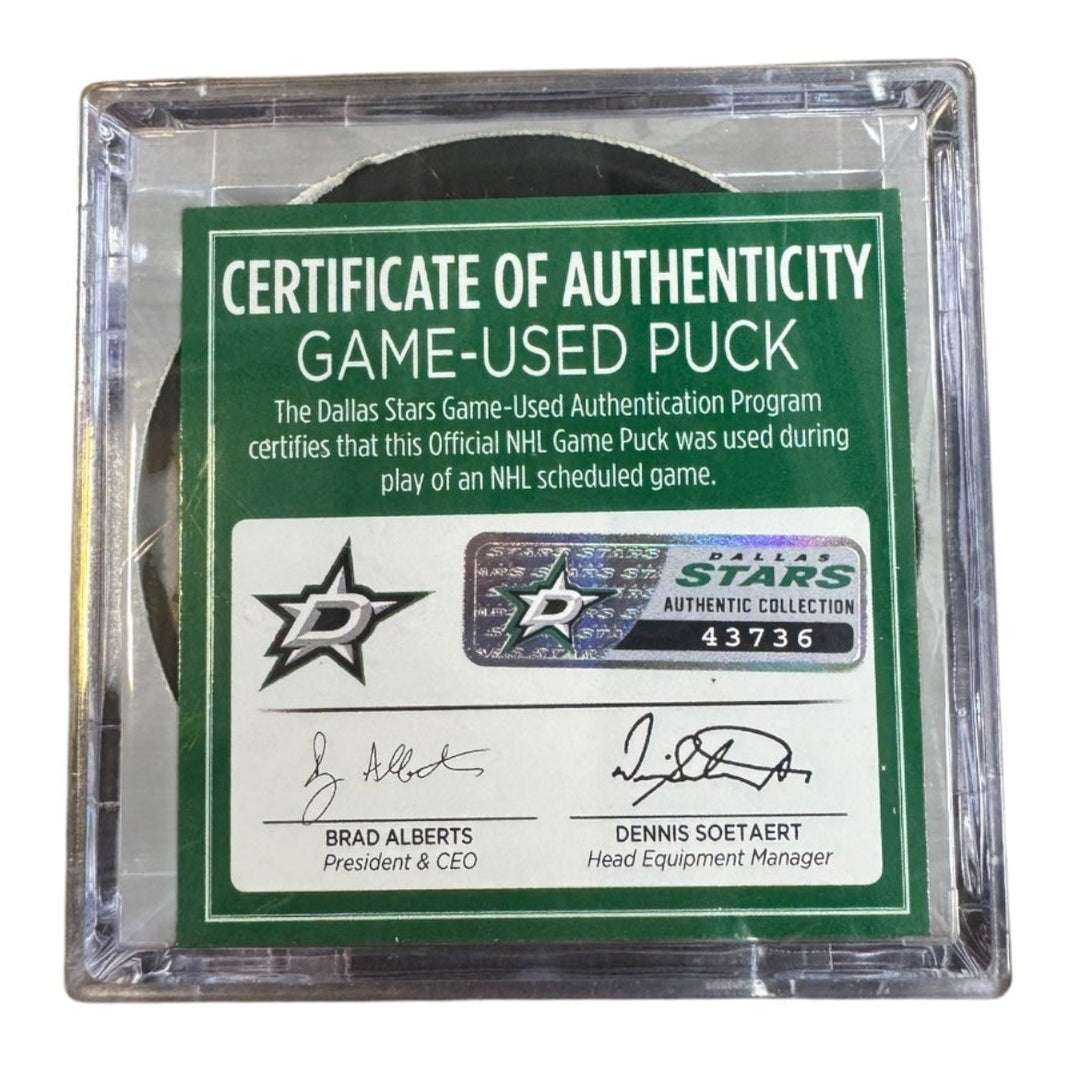A game-used hockey puck in a clear plastic protective case with a green and white Certificate of Authenticity insert. 
COA 