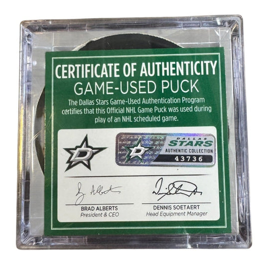 A game-used hockey puck in a clear plastic protective case with a green and white Certificate of Authenticity insert. 
COA 