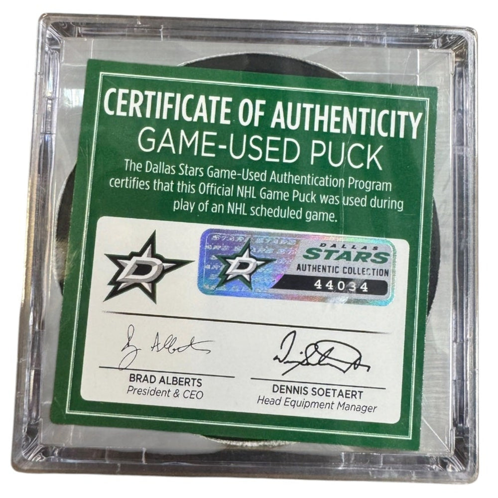 A game-used hockey puck in a clear plastic protective case with a green and white Certificate of Authenticity insert. 
COA #44034