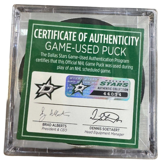 A game-used hockey puck in a clear plastic protective case with a green and white Certificate of Authenticity insert. 
COA 