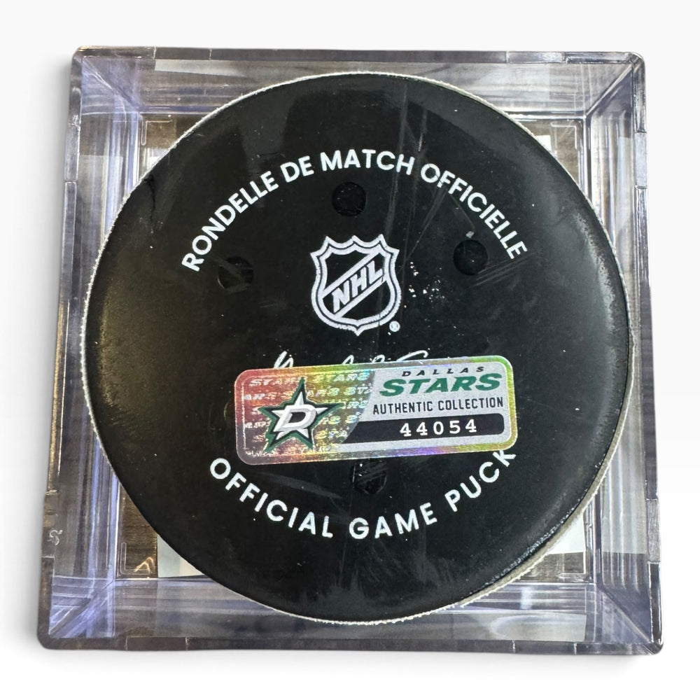 Official Dallas Stars NHL hockey game puck in a clear protective case, showing the black puck with white text and the Dallas Stars logo sticker.