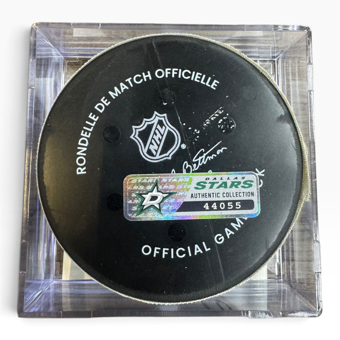 A NHL official hockey puck displayed inside a clear acrylic case, featuring a Dallas Stars authentic collection sticker.
