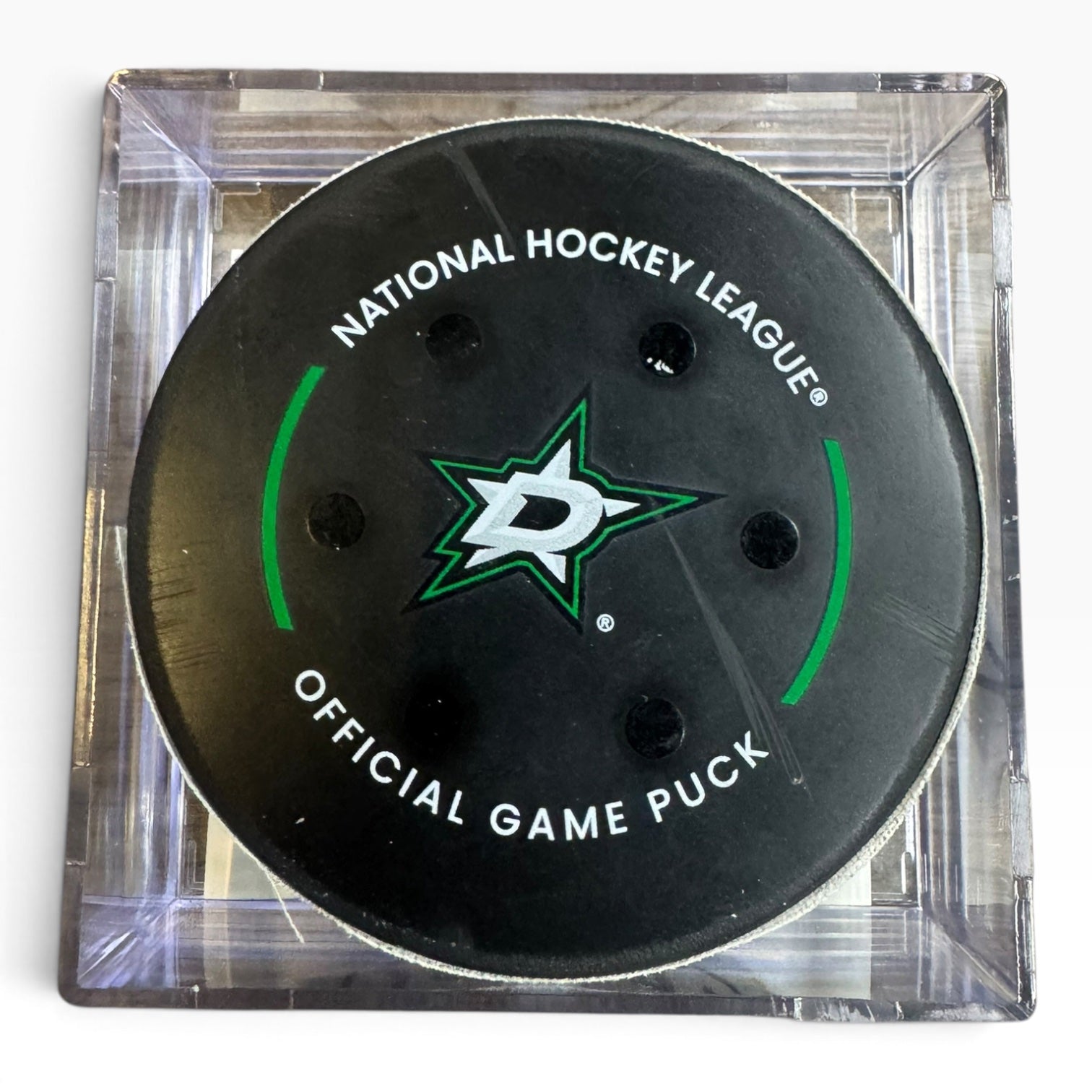 A Dallas Stars National Hockey League official game puck in a clear square plastic case, photographed from above on a white background.