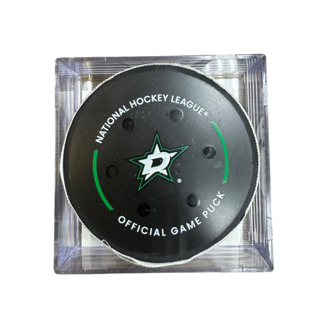 A Dallas Stars NHL official game/goal puck inside a clear plastic protective case, shown against a plain white background.
