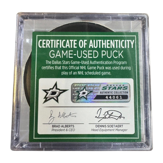 A game-used hockey puck in a clear plastic protective case with a green and white Certificate of Authenticity insert.  
COA 