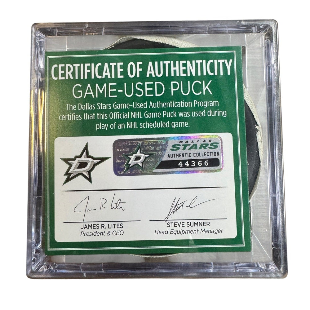 A game-used hockey puck in a clear plastic protective case with a green and white Certificate of Authenticity insert. 
COA #44366