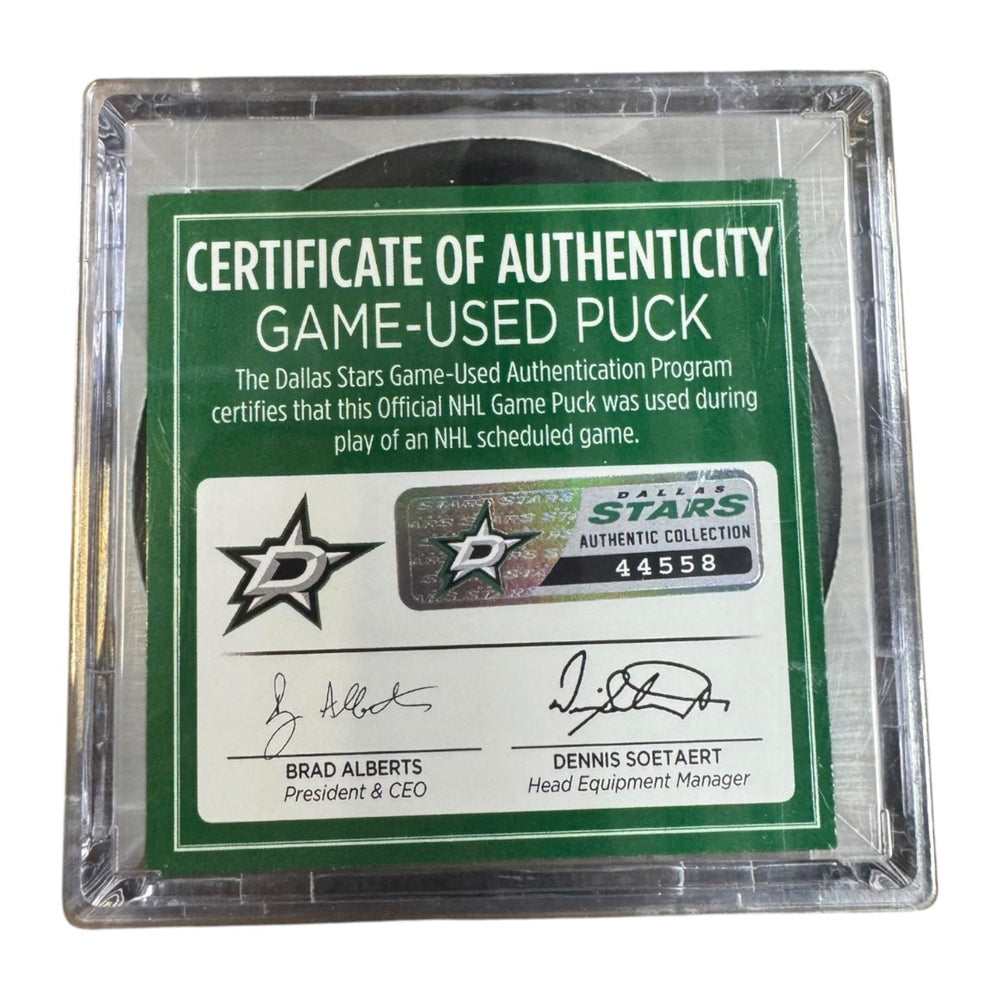 A game-used hockey puck in a clear plastic protective case with a green and white Certificate of Authenticity insert. 
COA #44558