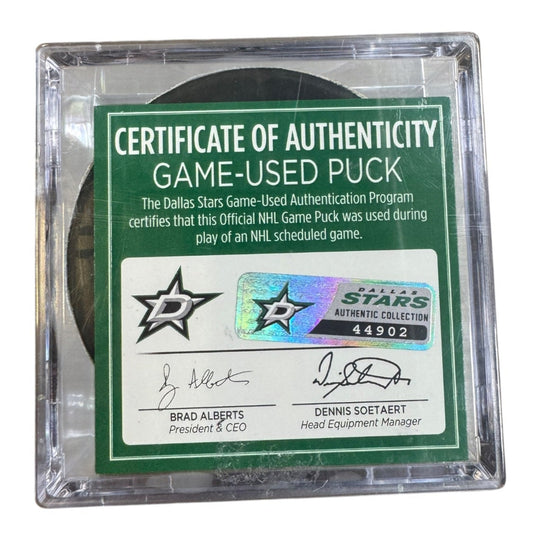 A game-used hockey puck in a clear plastic protective case with a green and white Certificate of Authenticity insert. COA 