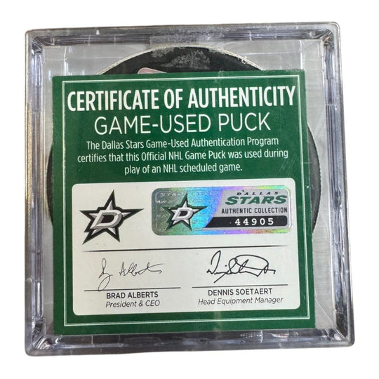 A game-used hockey puck in a clear plastic protective case with a green and white Certificate of Authenticity insert. COA 