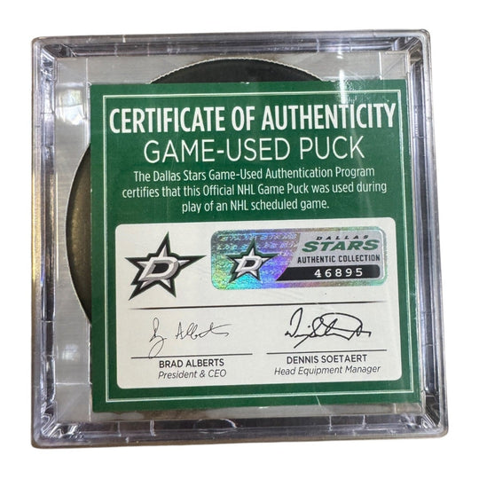 A game-used hockey puck in a clear plastic protective case with a green and white Certificate of Authenticity insert. COA 