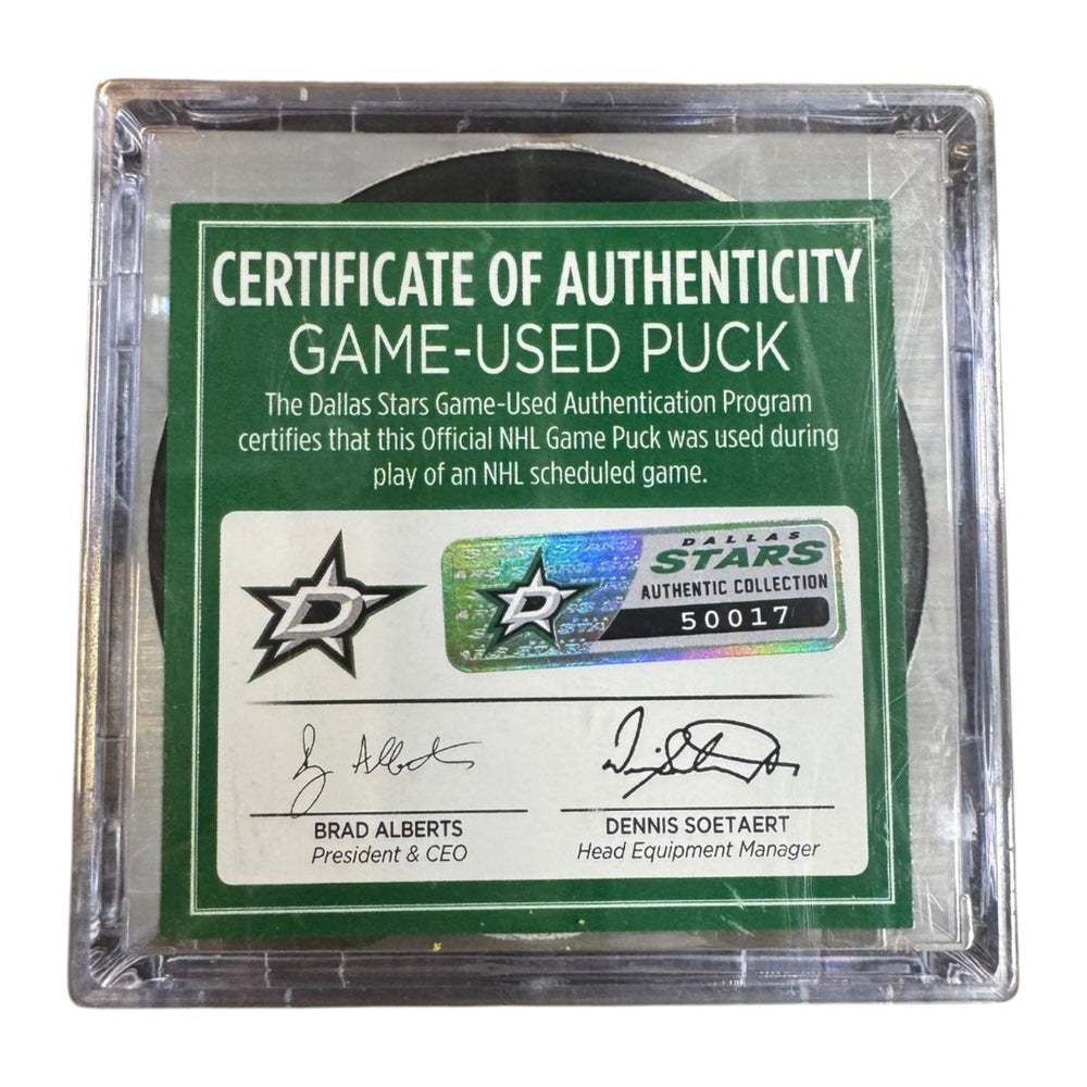 A game-used hockey puck in a clear plastic protective case with a green and white Certificate of Authenticity insert. COA #  50017