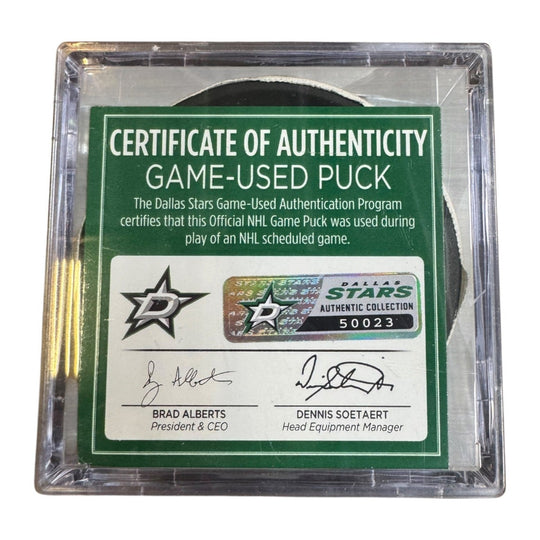 A game-used hockey puck in a clear plastic protective case with a green and white Certificate of Authenticity insert. COA 