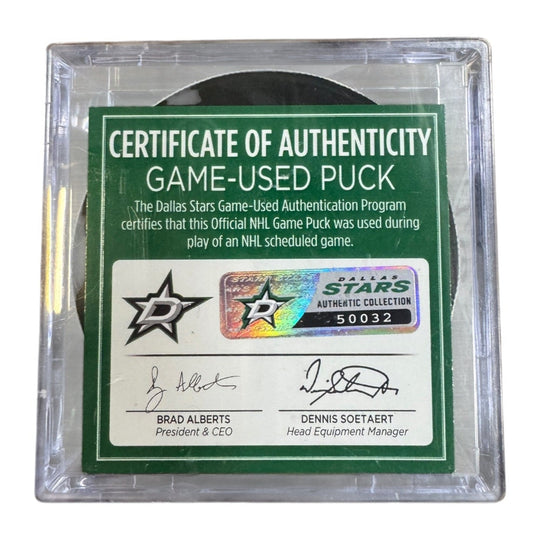 A game-used hockey puck in a clear plastic protective case with a green and white Certificate of Authenticity insert. COA 