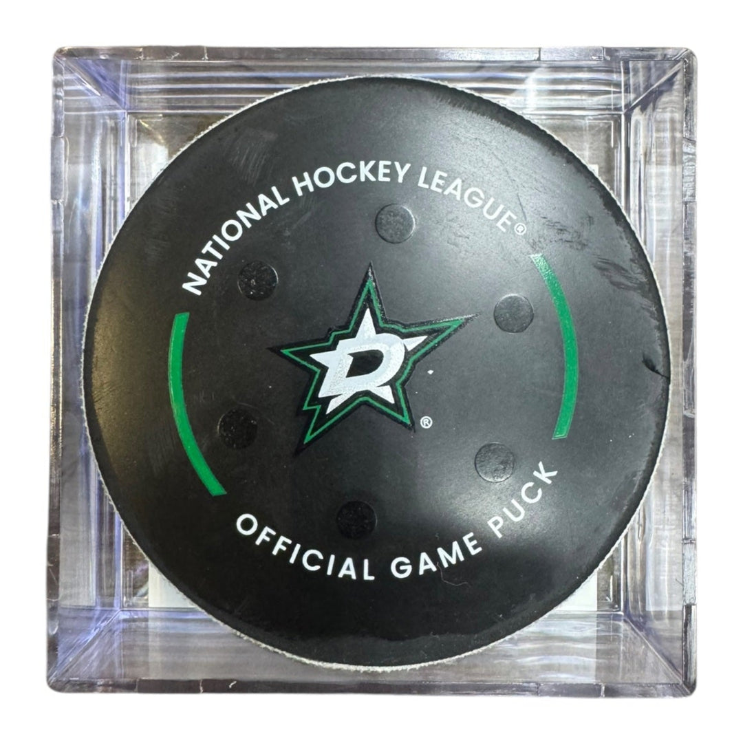 A Dallas Stars NHL official game/goal puck inside a clear plastic protective case, shown against a plain white background.
