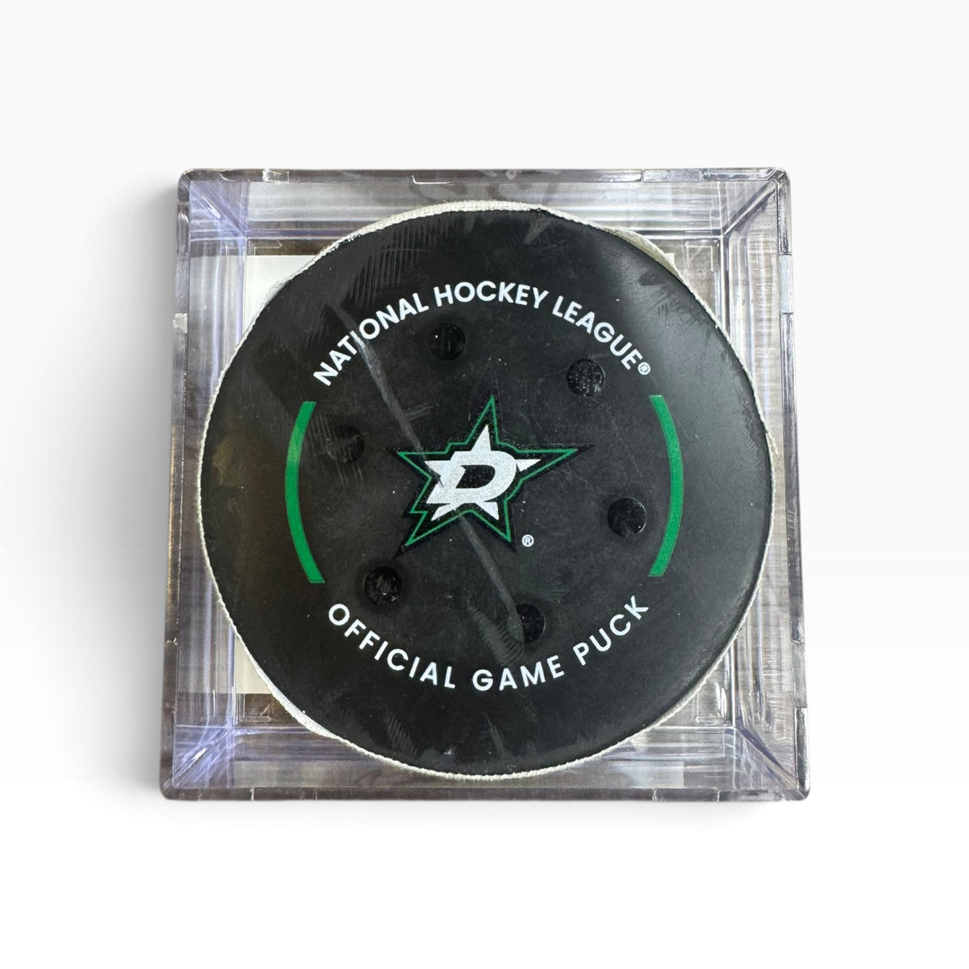 A Dallas Stars National Hockey League official game puck in a clear square plastic case, photographed from above on a white background.
